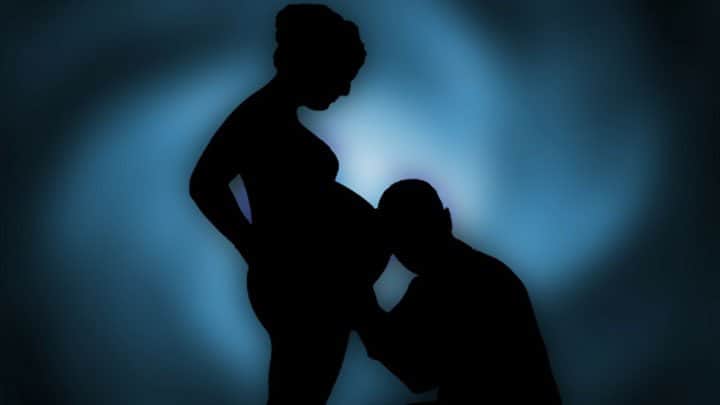 man listening to pregnant woman's bellu