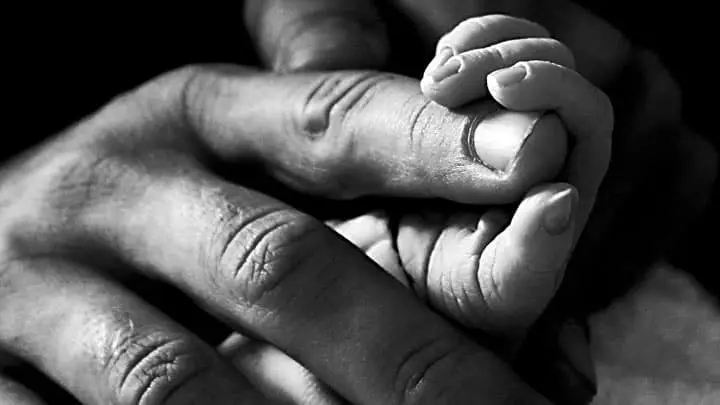 Infant holding fathers finger
