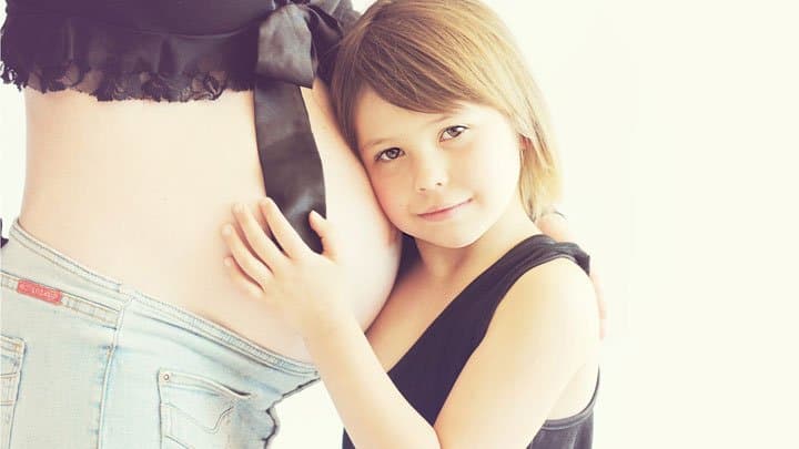 Daughter hugging moms pregnant belly