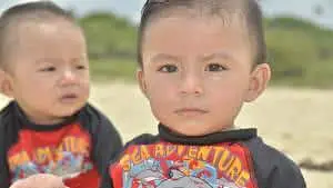 Identical twin boy toddlers at beach