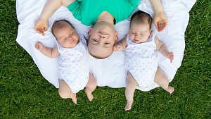 Twin baby girls on blanket with older brother