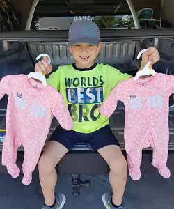 Older brother holding twin onesies 